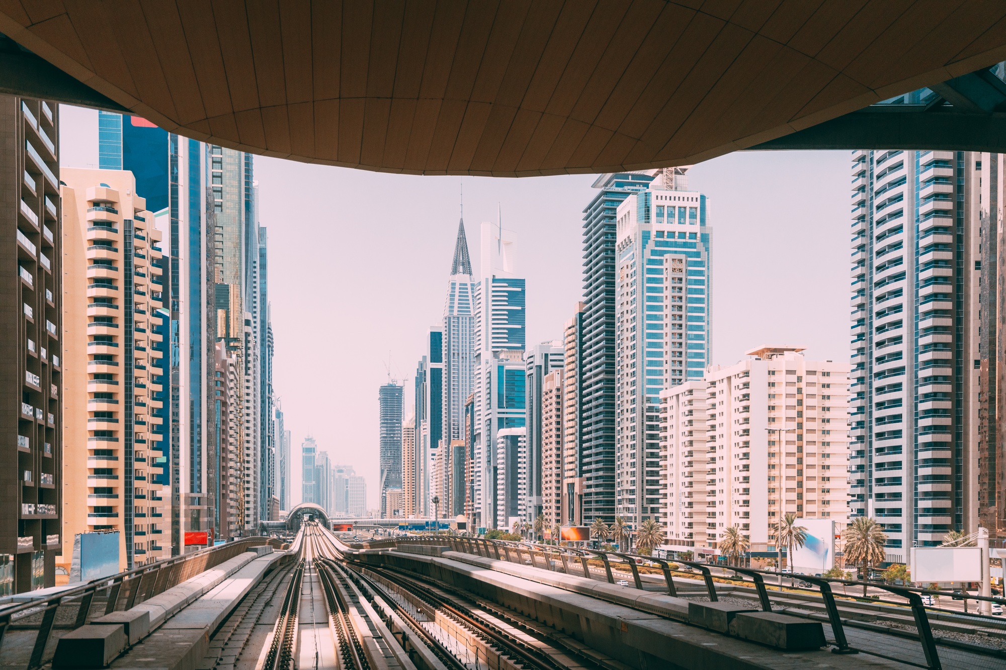 Modern Dubai Metro. Metro railway among glass skyscrapers in Dubai. Traffic on street in Dubai