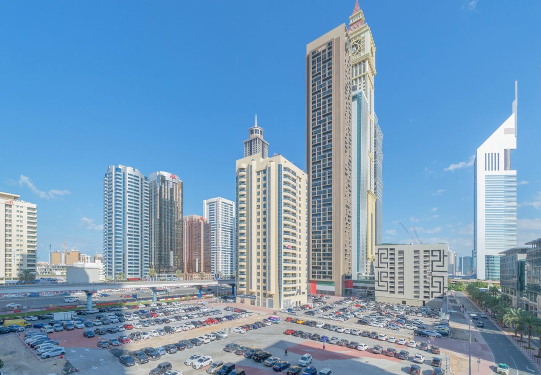 Aerial view of Dubai Downtown skyline with parking in United Arab Emirates or UAE. Financial district and business area in smart urban city. Skyscraper and high-rise buildings with blue sky at noon.